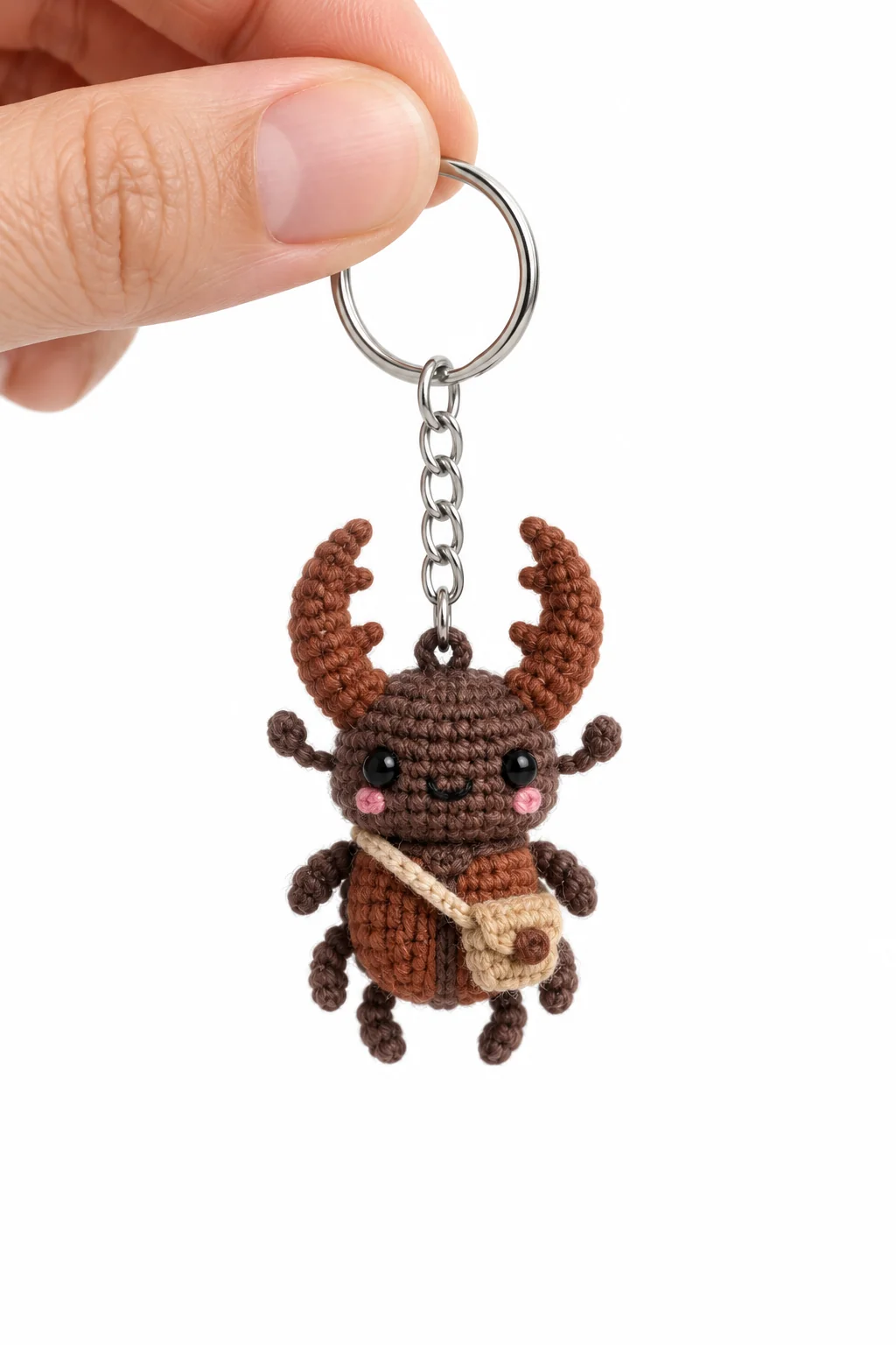 Brown crochet stag beetle keychain with curved antlers, a cream shoulder satchel and tiny waving arms