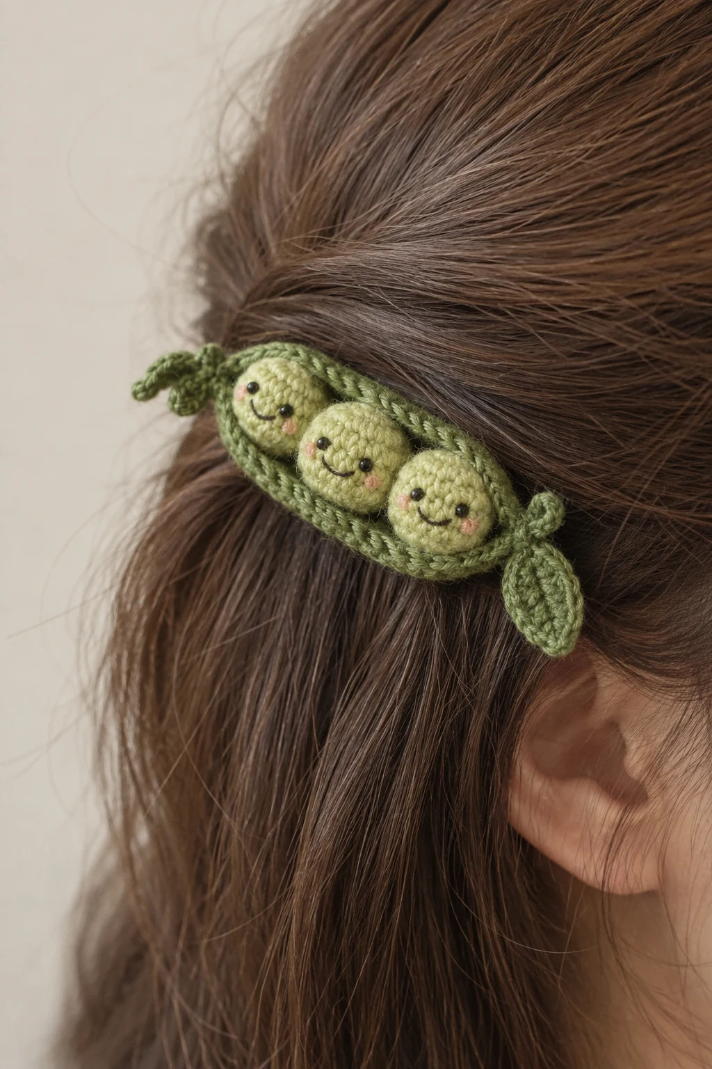 Green crochet pea pod hair clip with three smiling peas